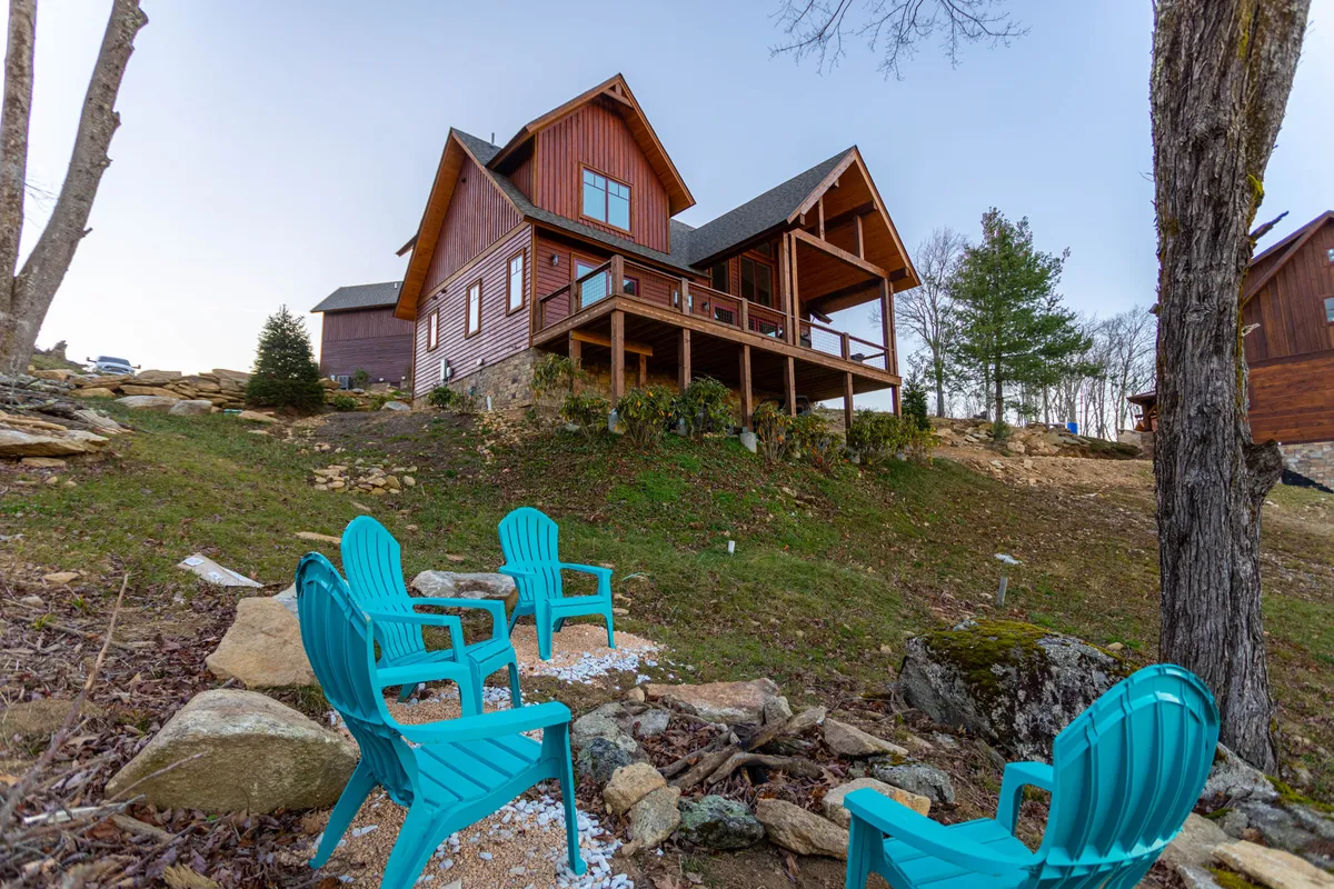 The cabin porch is furnished with turquoise chairs, surrounded by a landscaped area, and positioned for stunning sunset views. The setting feels cheerful and welcoming, ideal for morning coffee, sunset drinks, and time spent outdoors with friends, family, or pets.