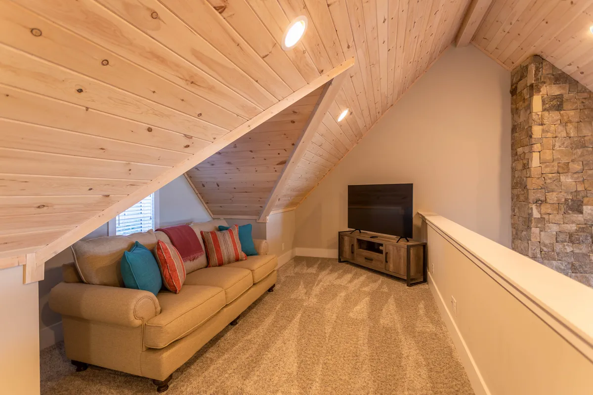 A stylish, comfortable living space with a sofa adorned with colorful cushions, a stone accent wall, and a television. The setup is perfect for relaxed movie nights or quiet evenings with loved ones.