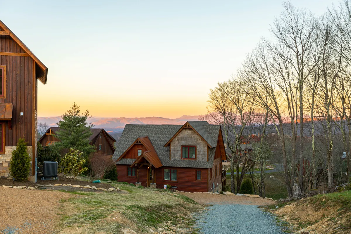 This exterior shot captures the main house set against a sweeping mountain backdrop at sunset. The inviting porch, open green spaces, and surrounding natural beauty hint at opportunities for outdoor barbecues, family gatherings, and easy access to nearby trails and amenities.